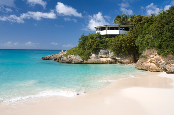 A house on a small cliff overlooking an uncrowded beach on in Anguilla, Eastern Caribbean.