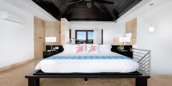 The master bedroom of Sea Edge Villa has a king size bed, en-suite bathroom, patio, large soaking bathtub, TV, and spectacular ocean views.