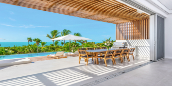The expansive, glass, sliding doors open from the great room to the covered terace at this Turks and Caicos luxury villa rental.